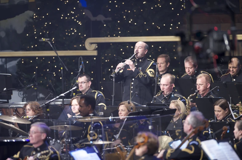 conductor wearing uniform speaking with band playing with lighted background