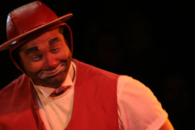 a man in red vest and white shirt wearing hat