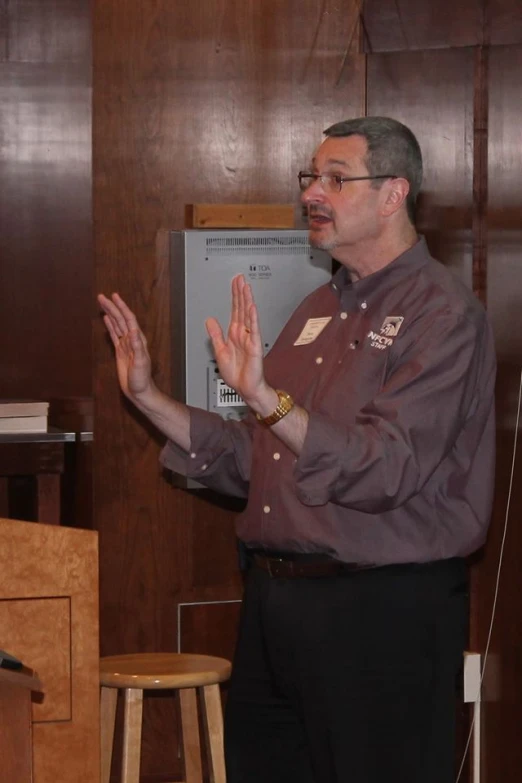 a man wearing glasses stands in front of a podium