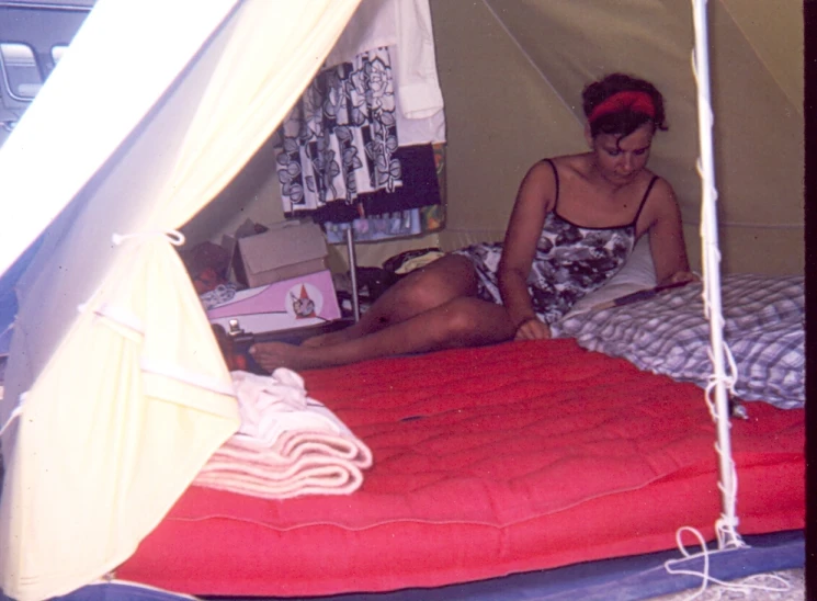 a woman sitting in the corner of a tent on top of her bed