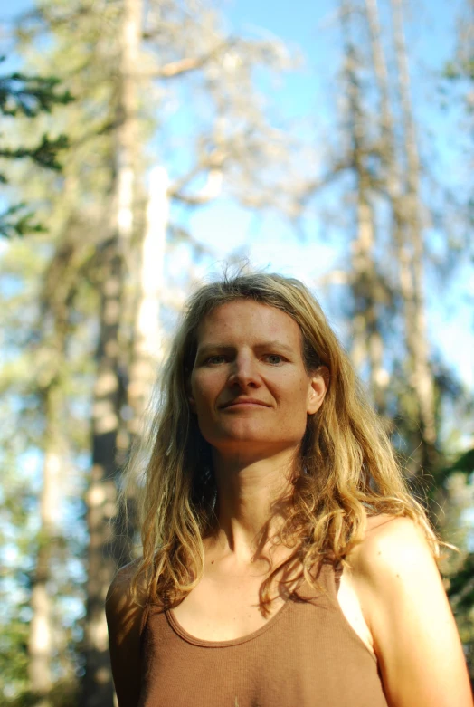 a woman poses for the camera in front of the woods