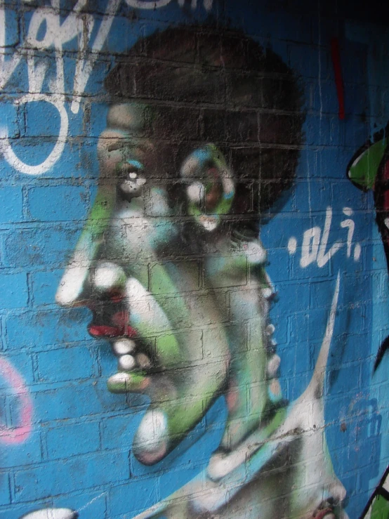 a wall painted with graffiti and features a face and words on it