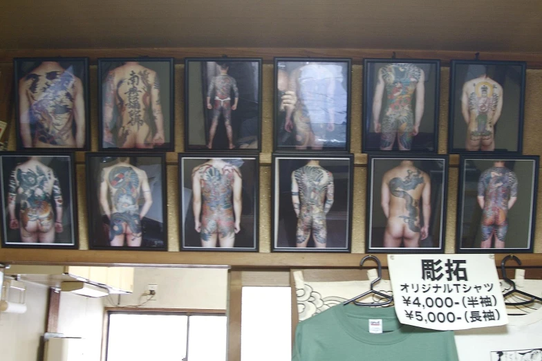 a man with multiple tattoos stands next to a display of shirts