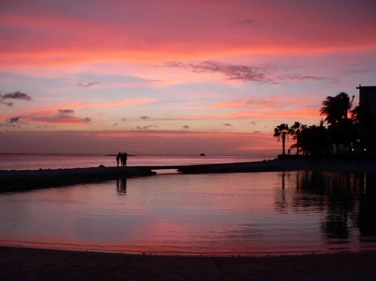 people are walking on the beach during sunset