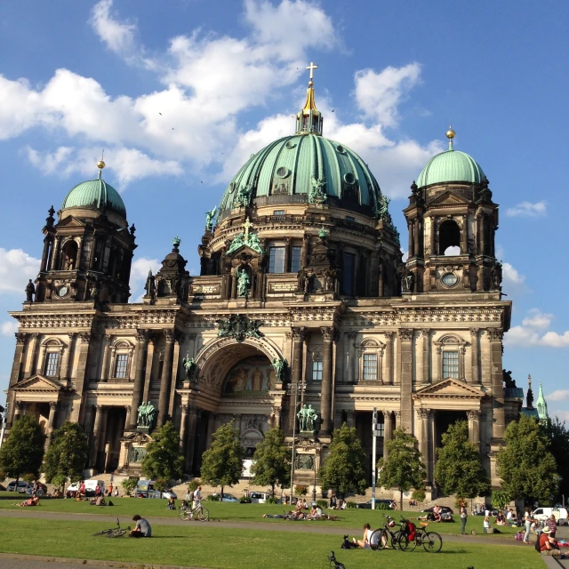 an ornately designed church surrounded by greenery on a sunny day