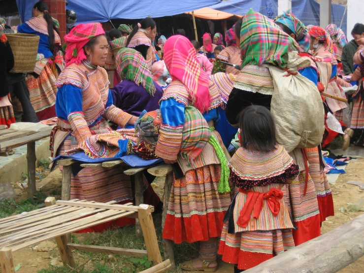 some woman in colorful cloth dresses near some tents
