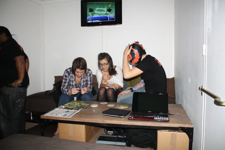 three young women sitting on couches watching two men play wii games