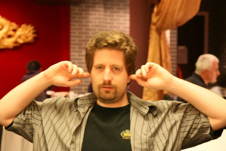 a man standing up to a camera with his hands in the ears