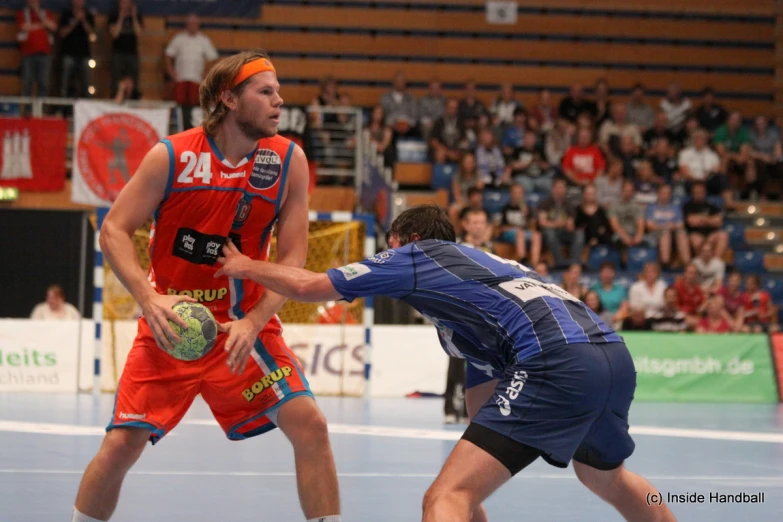 two men playing in a indoor game, one trying to grab the ball with his hand