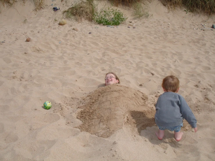 two children playing in the sand at the beach