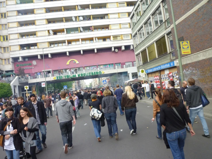 a crowd of people walk under an overpass