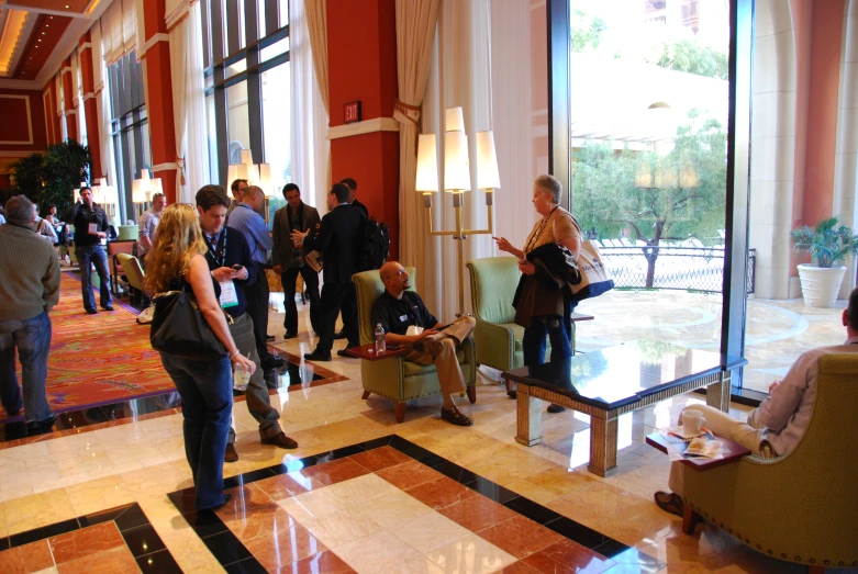 people gathered at various tables in lobby with large windows