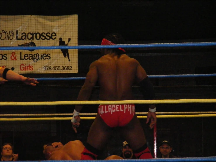 two men standing on the ropes while one holds a towel