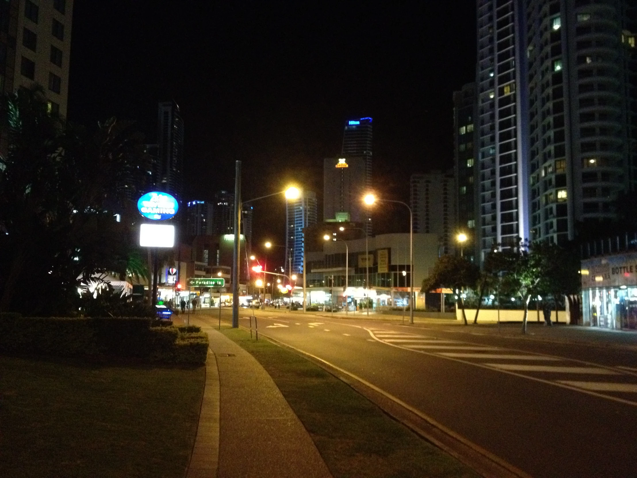 an empty city street at night with lights and some buildings