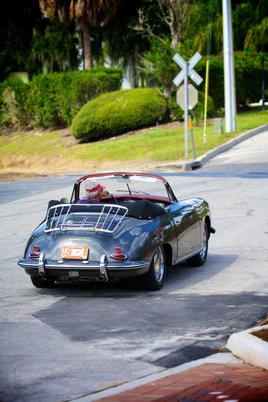 a porsche with the top down driving around a corner