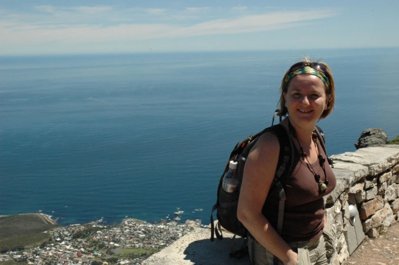 a women who is standing on a wall near water