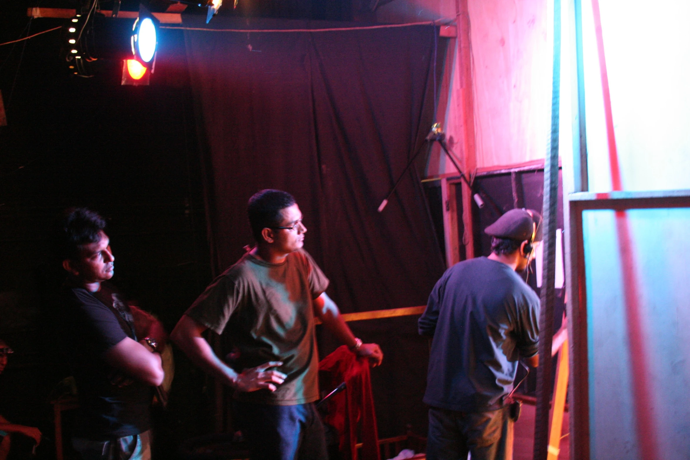 three men look on as they stand near a red and blue light