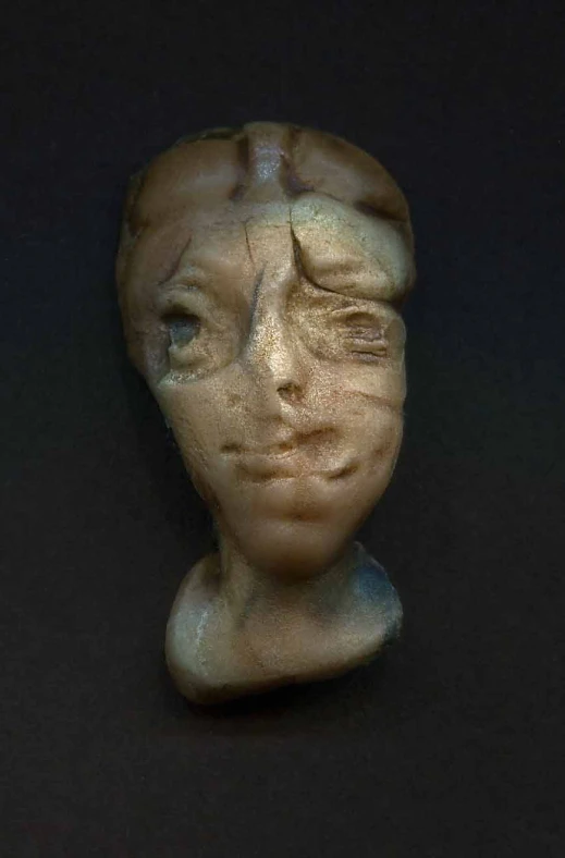 a white, clay head sitting on a black surface