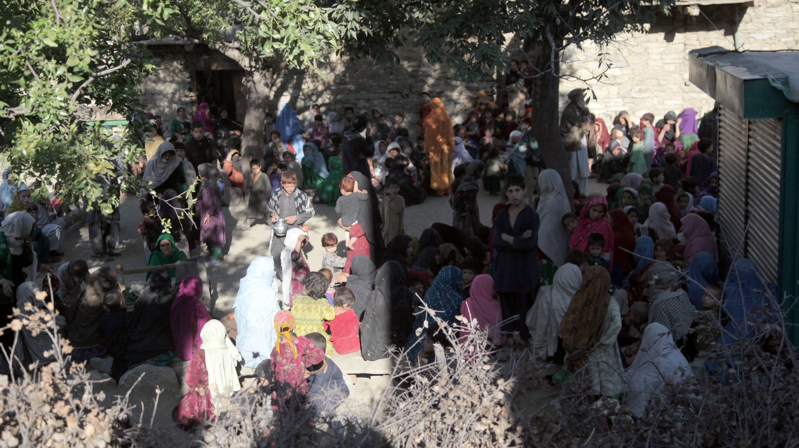 people in colorful dresses gather near a brick building