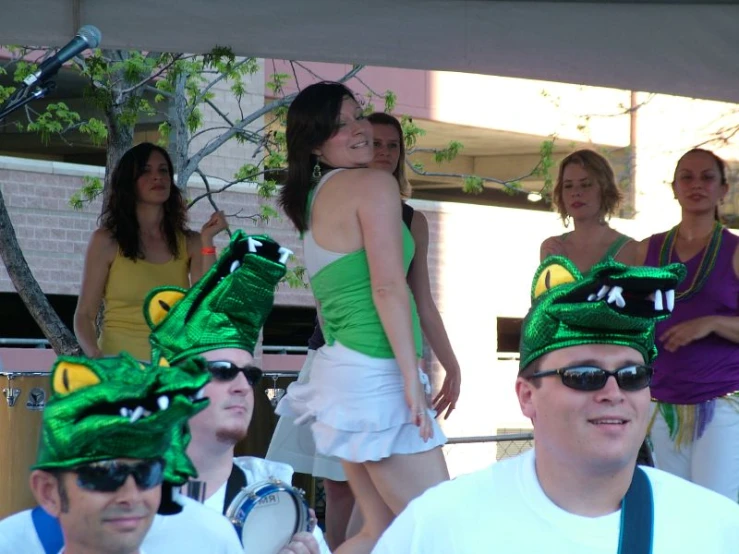 people standing with people in costumes, and one woman wearing a green dress