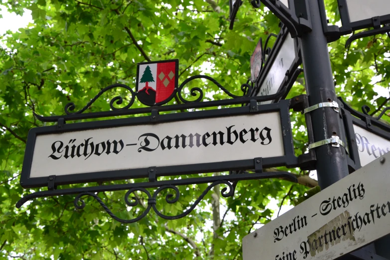 a sign hanging from a pole on a pole under a tree