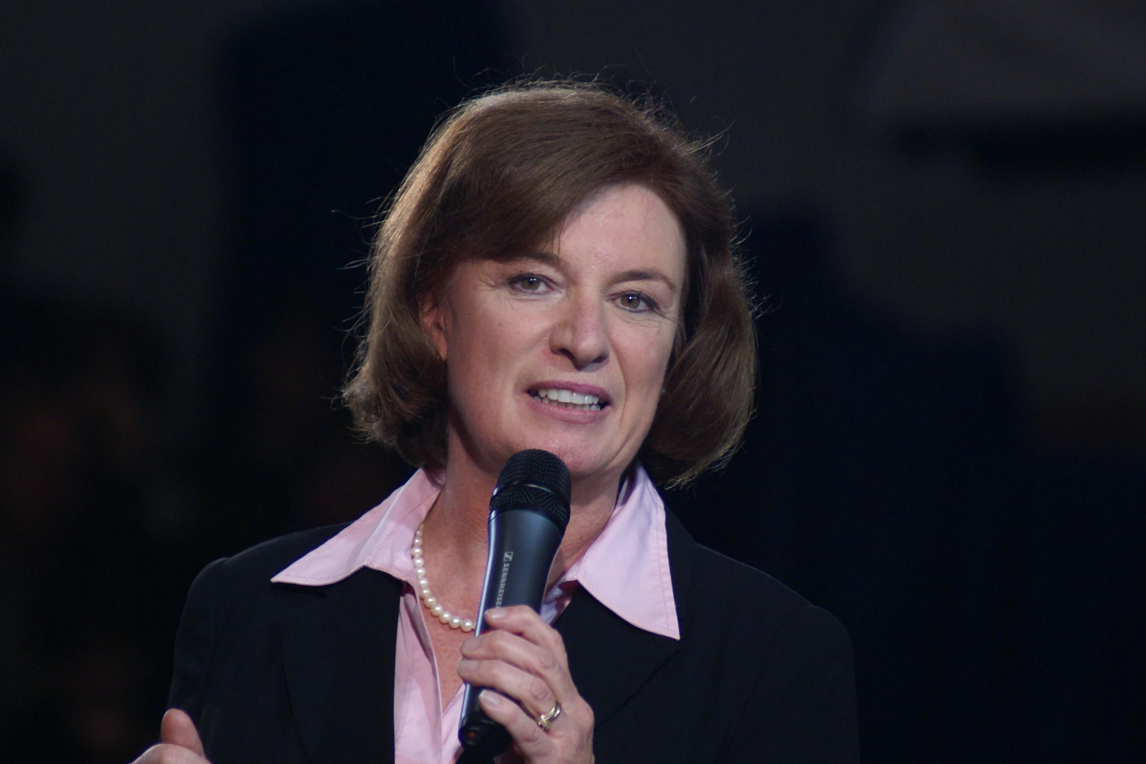 a woman is speaking into a microphone while smiling