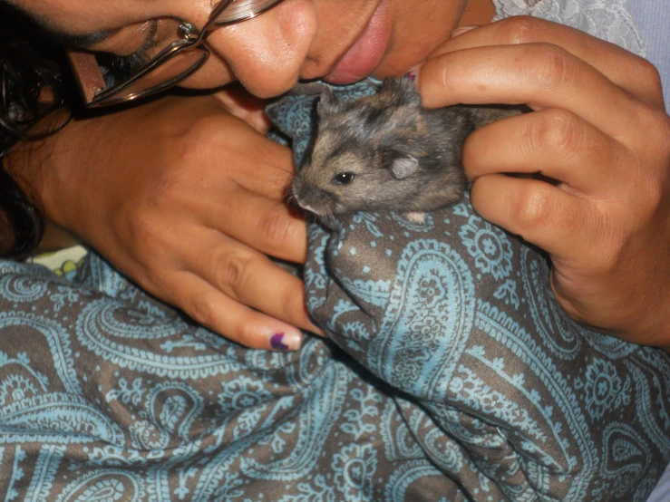 a woman is holding a little hamster inside of her hand