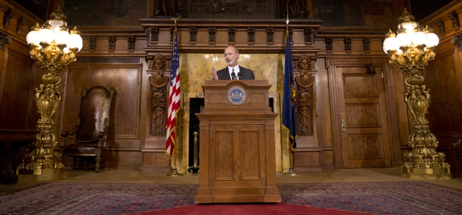 a speaker speaks at a podium with american flags