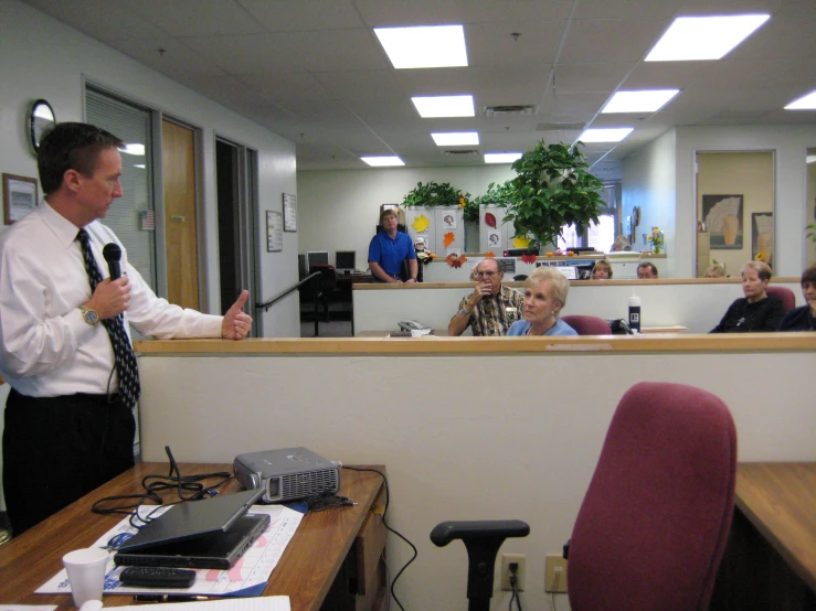 two men and women speaking into microphones in an office setting