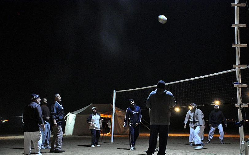 several young men are playing volleyball together at night