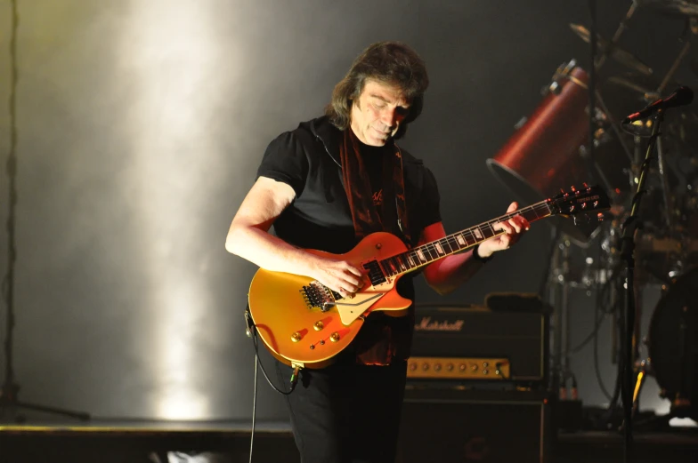 a person that is playing a guitar in front of some microphones