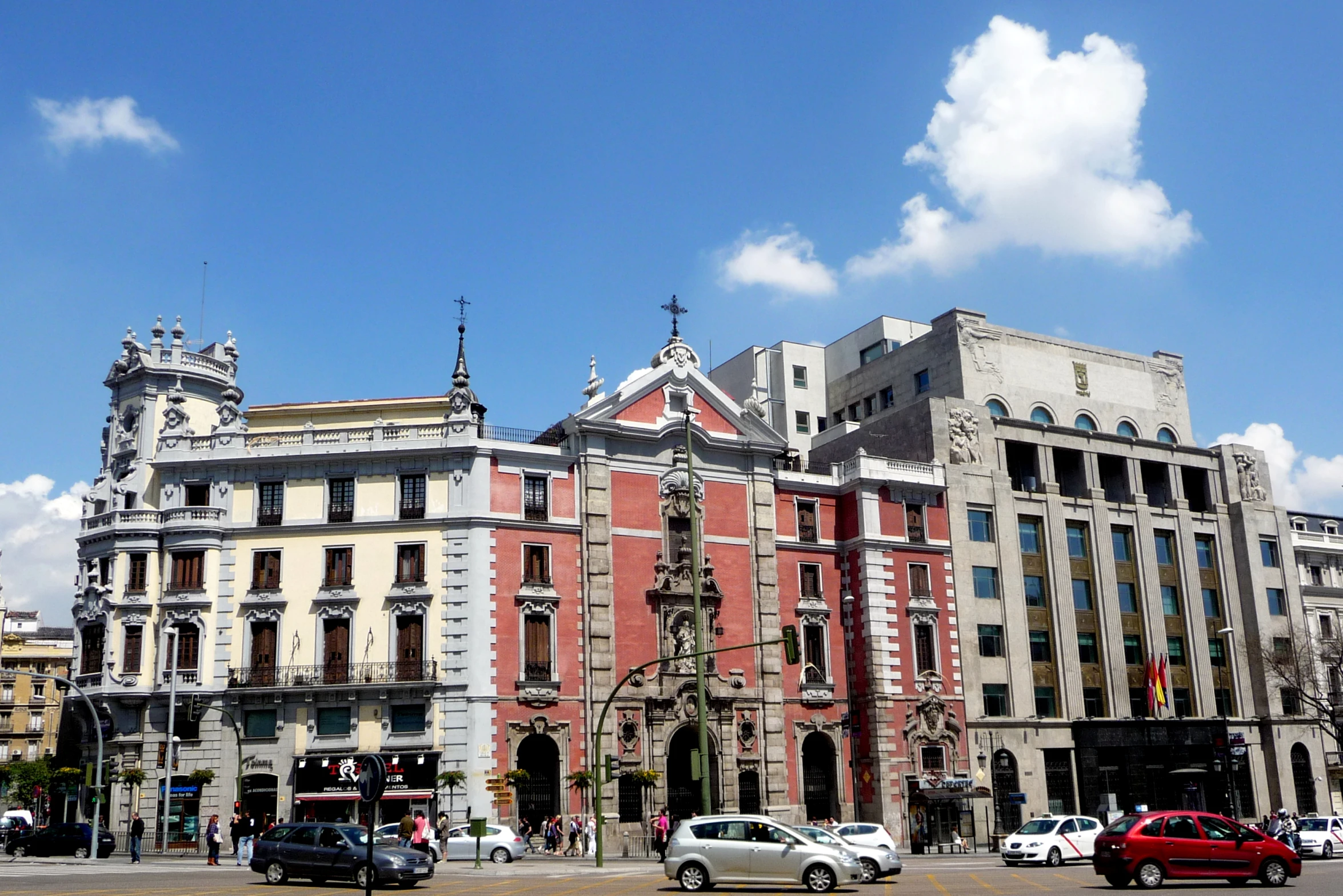 the sky is partly cloudy as it passes by buildings on a street corner