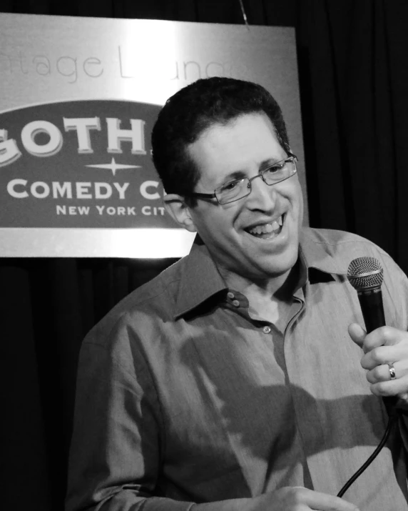 man standing behind microphone and smiling at audience