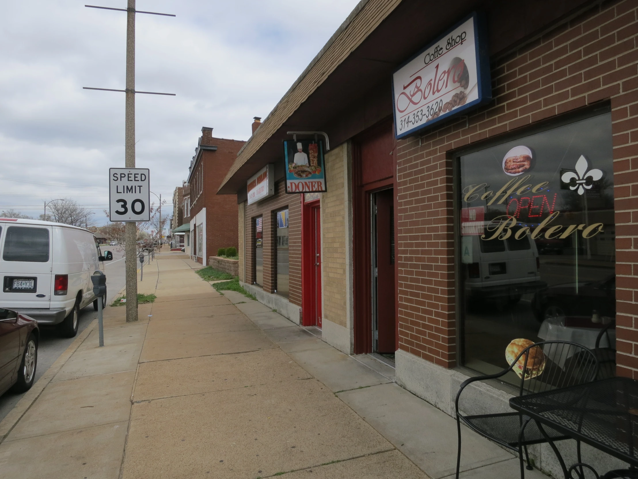 a street corner with signs and a sidewalk chair in front of buildings