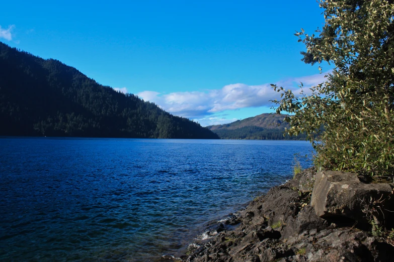 a body of water with mountains on one side and hills in the background