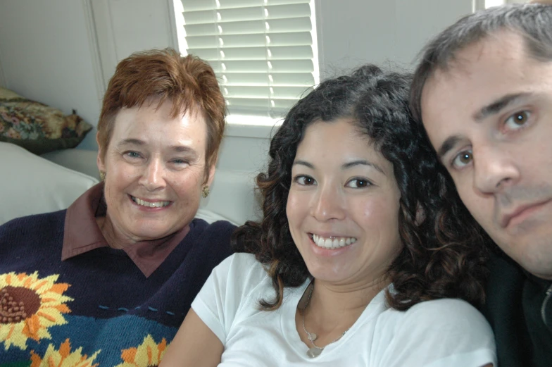 three people posing for a picture on a couch