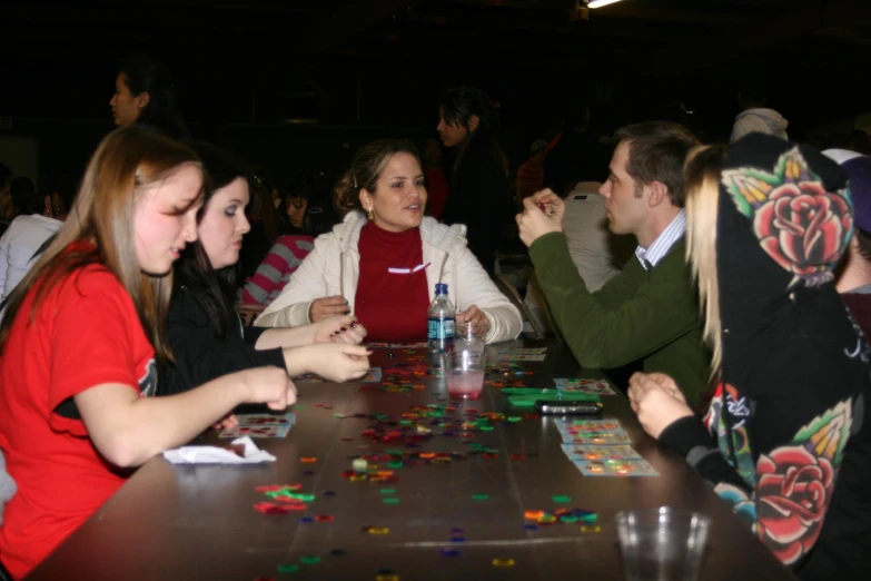 a group of young people sitting around a wooden table