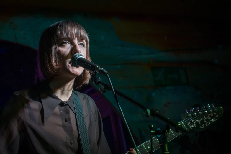 a young woman with long hair wearing a suit and tie singing into a microphone