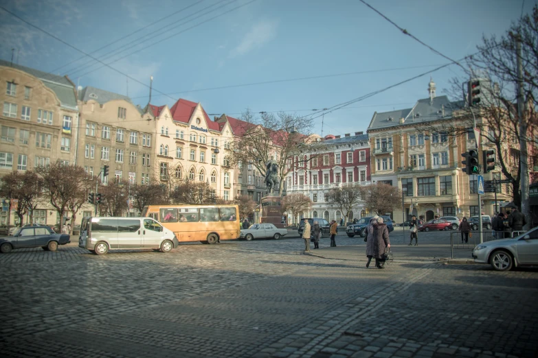 a busy intersection with several people crossing and several vehicles