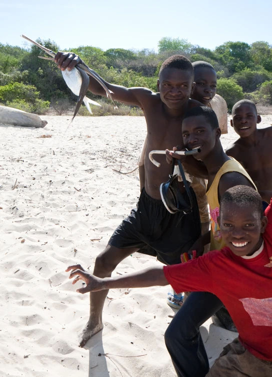 four boys pose with a big fish on the beach