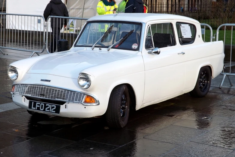 a white, restored car in front of a crowd