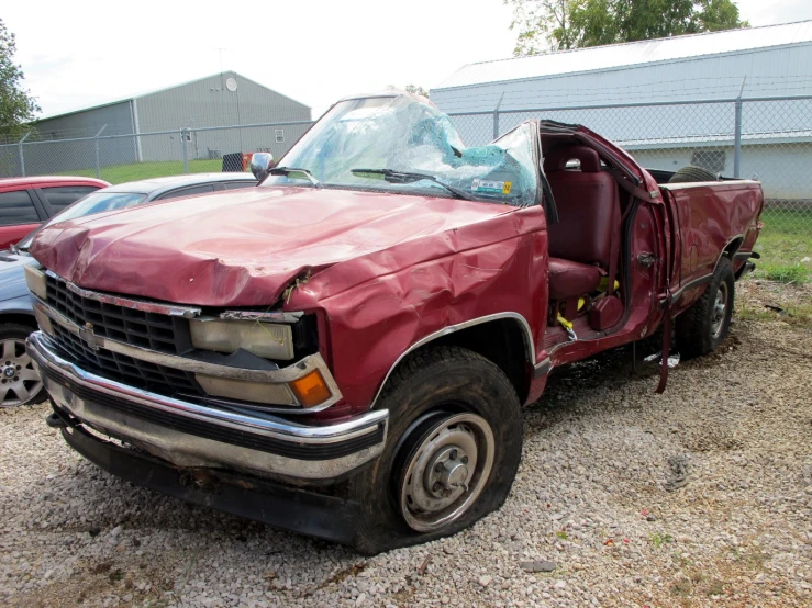 the red truck is sitting in a gravel lot