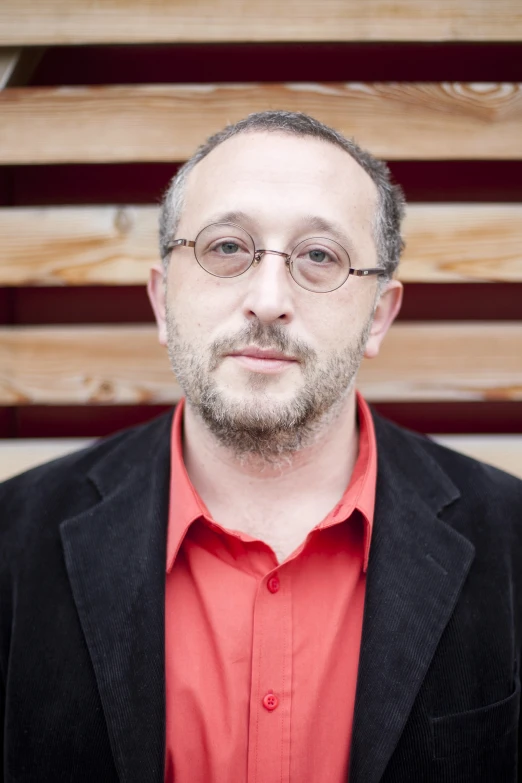 a man in a suit jacket and eyeglasses posing for a pograph