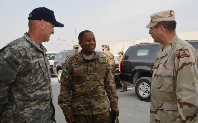 men in military uniforms talk together in a parking lot