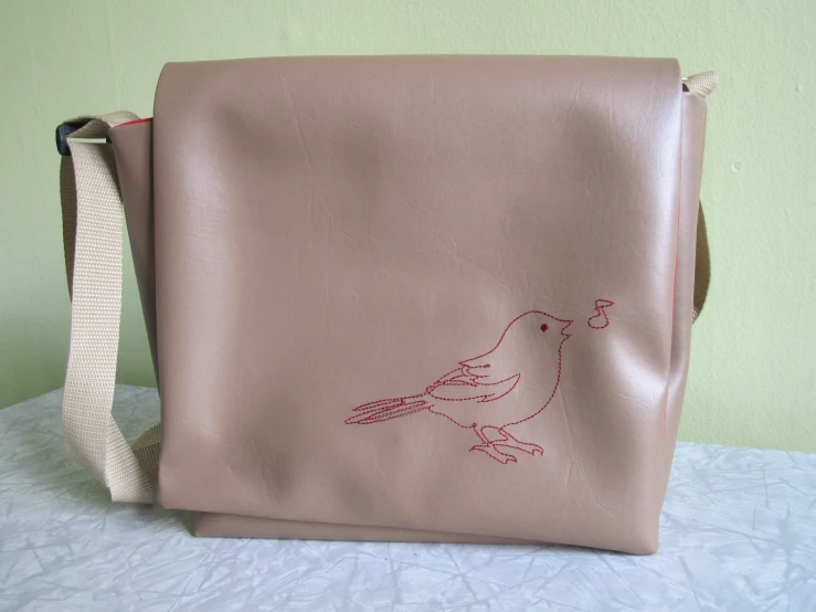 a bag is on the bed and has a bird drawn on it