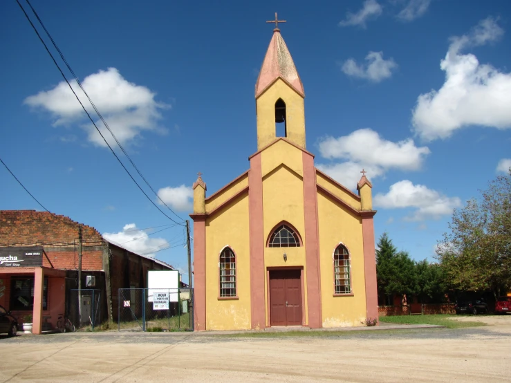 a church with brown walls has a red and brown cross on the front