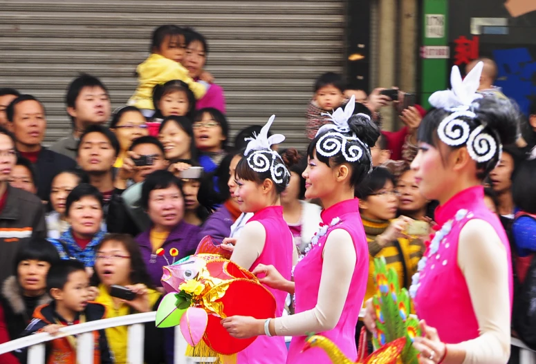 a group of girls with hats and body suits walking on a street in front of people