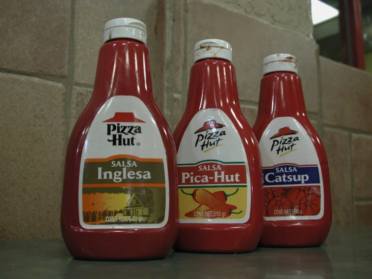 three bottles of pizza hut sauce on a counter top