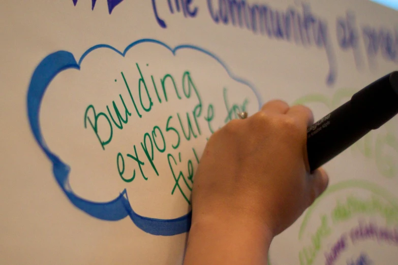 a hand writing on the whiteboard of an exhibit