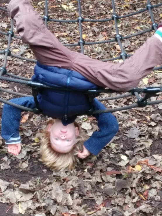 a little girl upside down on the swing